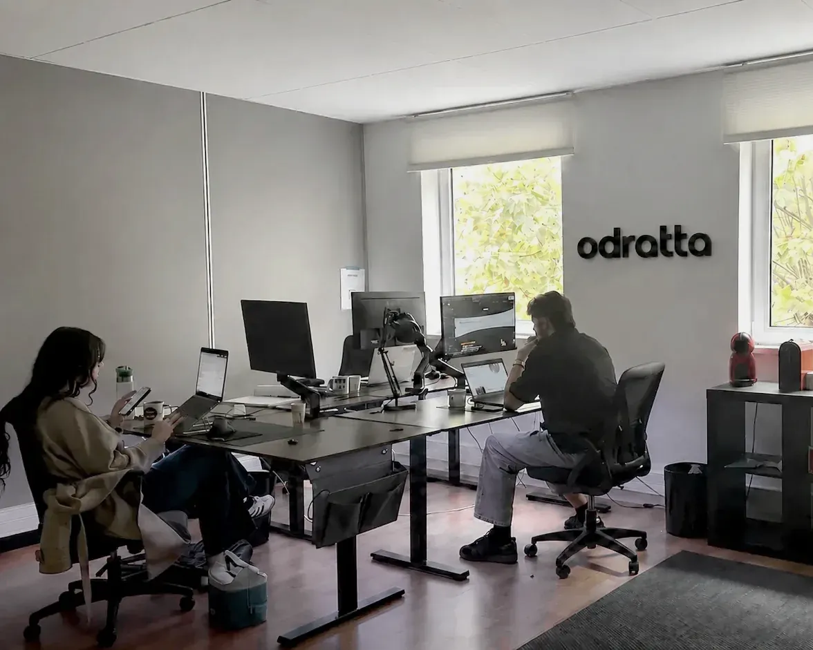 Les bureaux d’Odratta à Grenoble : deux personnes à leur poste, l’enseigne odratta au mur, une fenêtre ouverte sur les arbres.