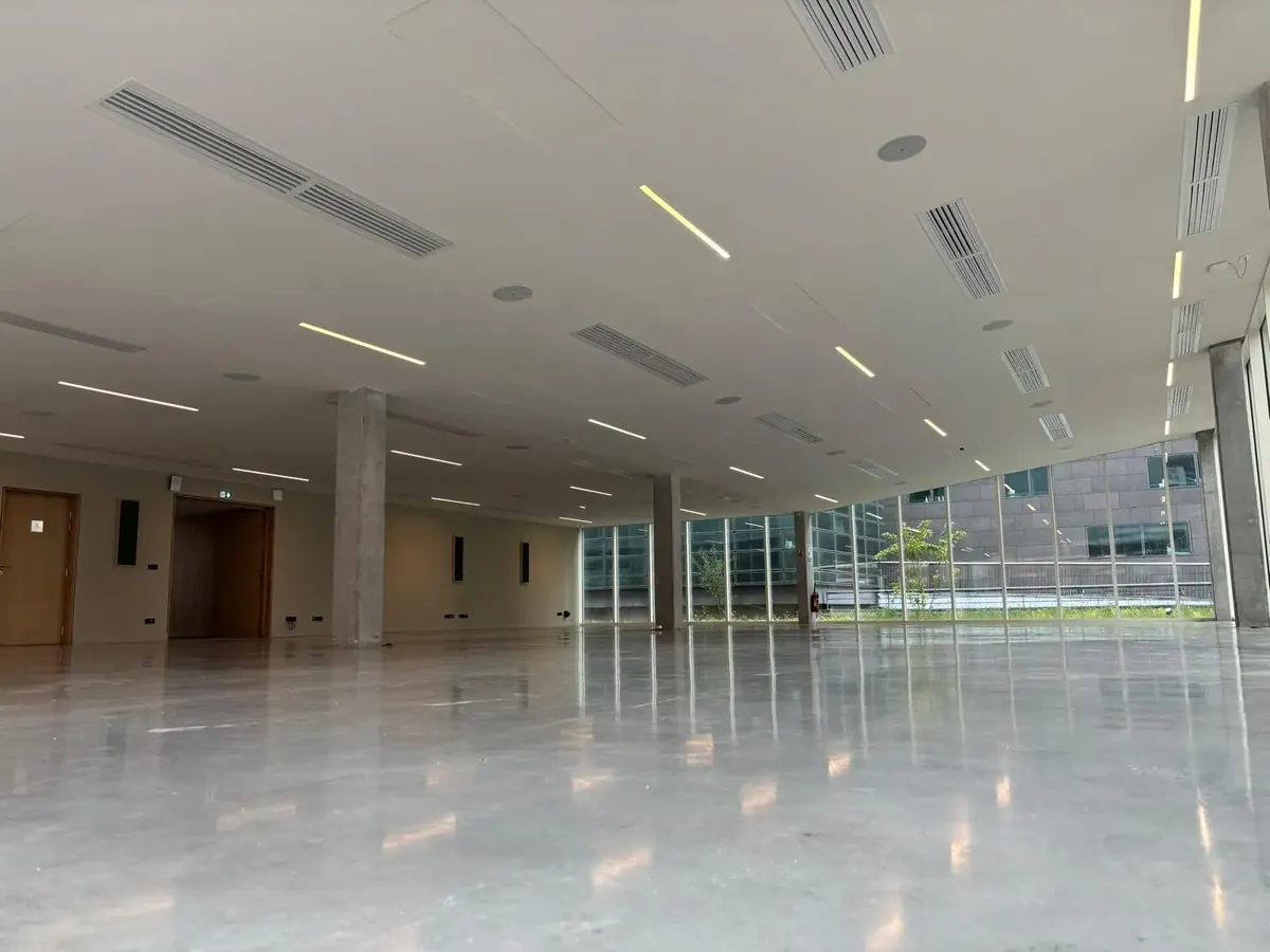 Plateau de bureaux de l’Institut Pasteur de Lille sous plafond continu, réglettes alignées.
