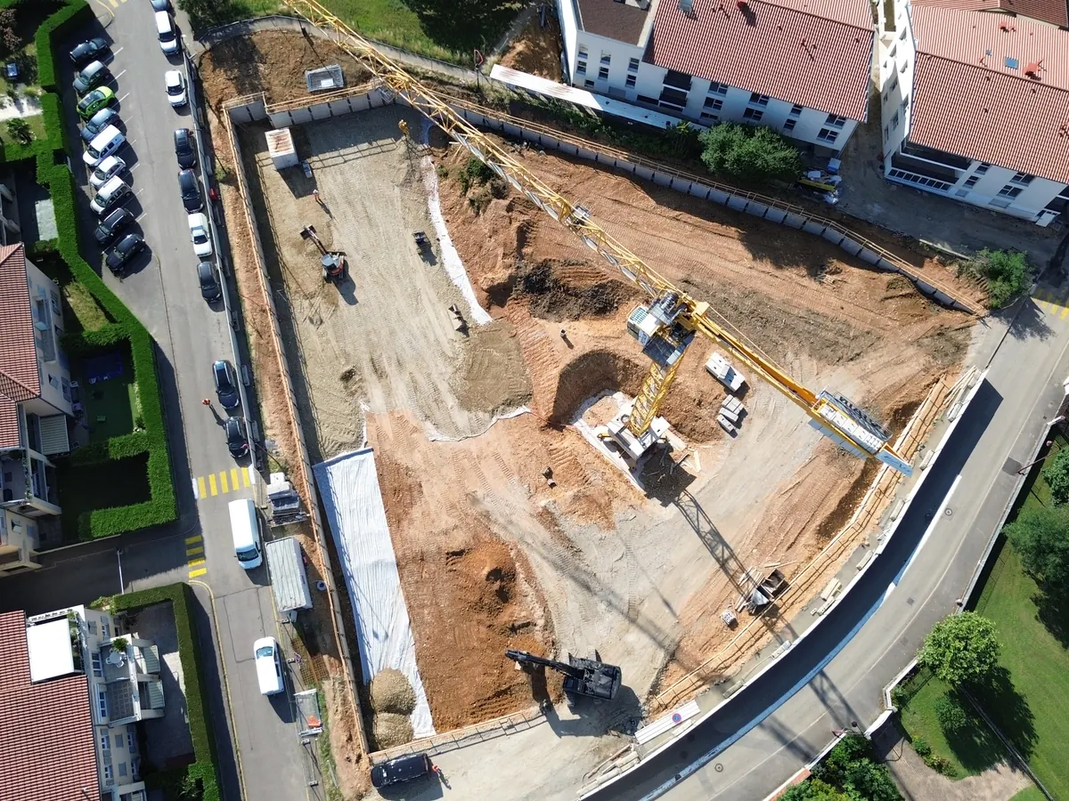 Vue au drone du terrassement du chantier de Ternay, entre des maisons et une route.